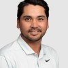 Jason Day, Smiling at the camera. He has black hair, brown eyes and is wearing a white shirt. He is in front of a white background