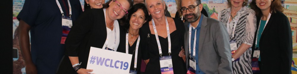 Group of patient research advocates standing together holding a sign that reads #WCLC19