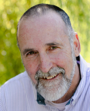 Image of man smiling at the camera he is wearing a white striped shirt