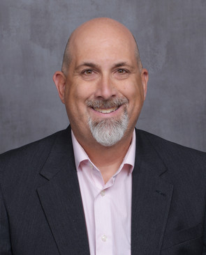 Man wearing pink shirt with suit jacket smiling at camera